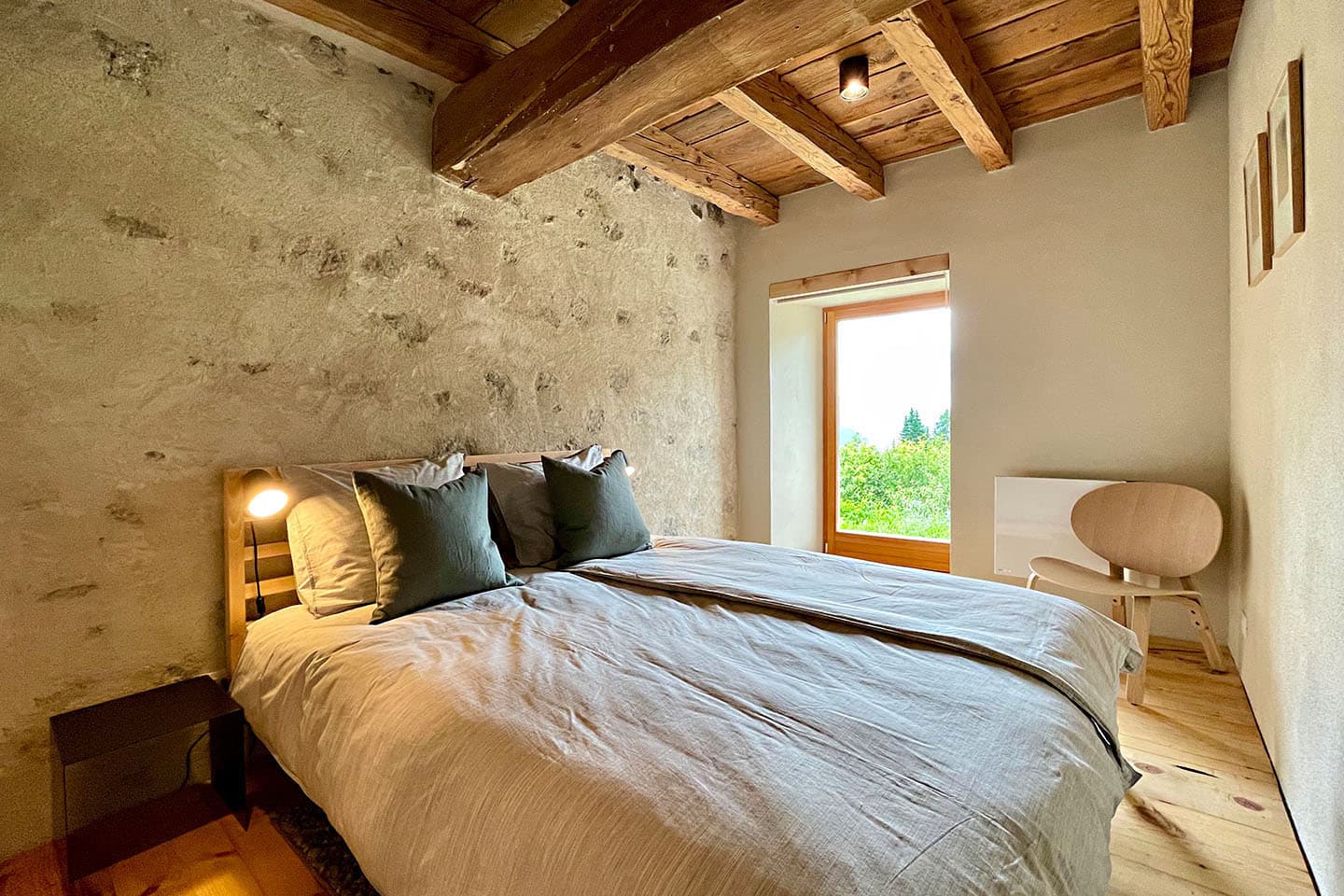 A bedroom with exposed stone and beamed ceiling