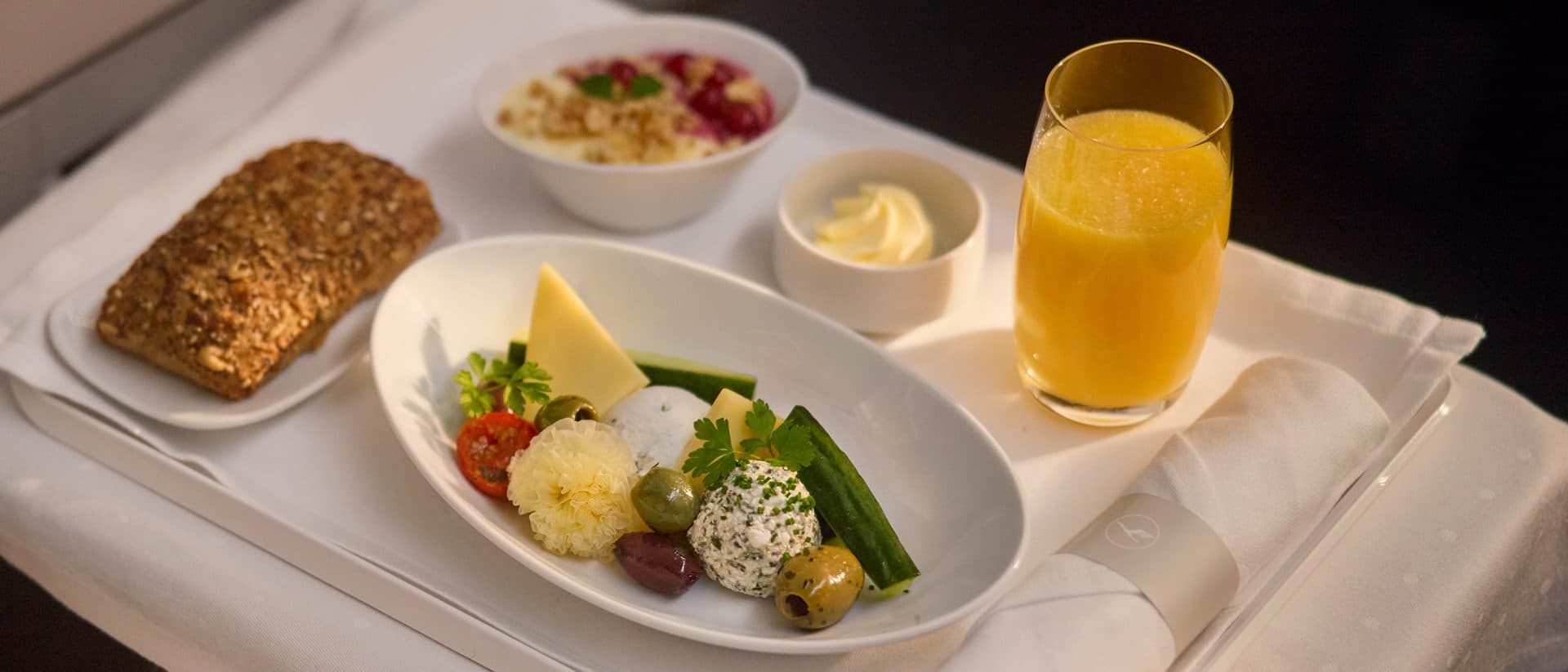 A Business Class tray with cheese, yogurt, bread, and orange juice