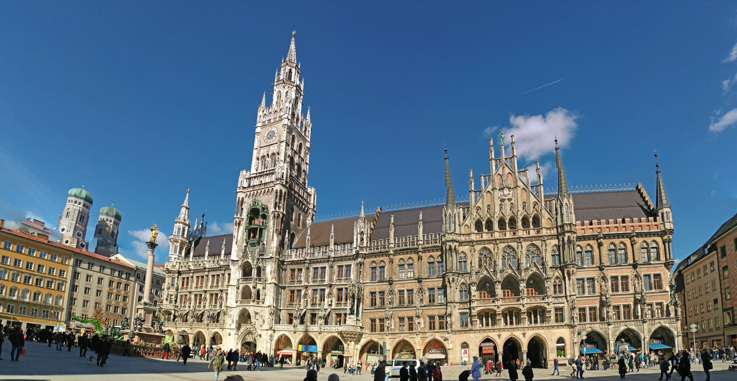 The Neues Rathaus tower rising into a clear sky over Marienplatz, with the Frauenkirche's domes at left