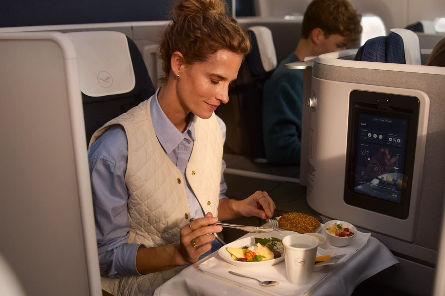 A passenger enjoying a plated meal at her business class seat